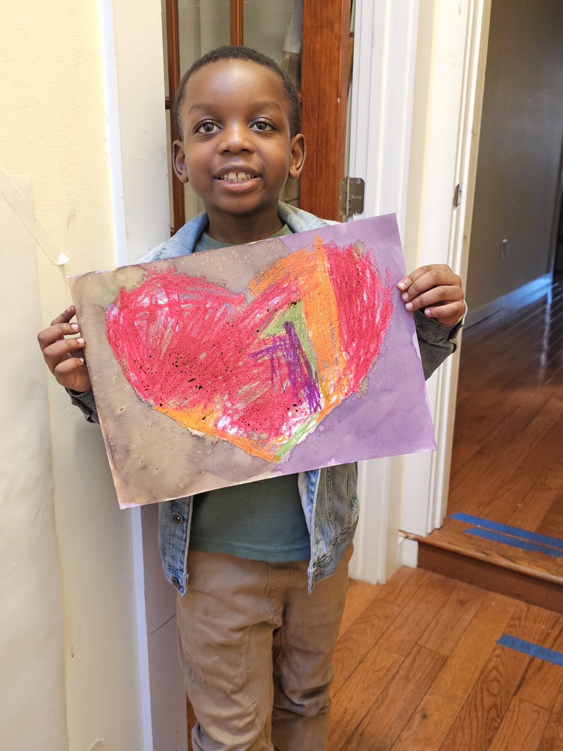 The cover photo for the November 2024 Newsletter. Shows a student holding up their drawing and smiling