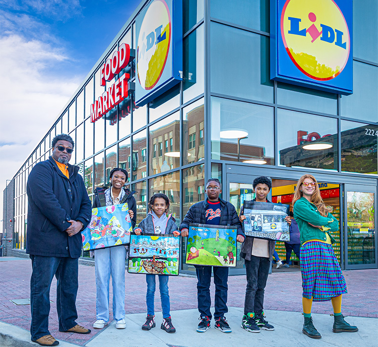 2 teachers and Akilah Daniels, Gabriel Trembath-Nicholson, Nyzear Allen and Zoe Amen holding up shopping bags with their art printed on them outside Lidl (David Keith Photography)